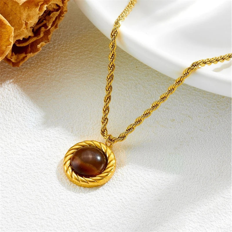 Gold necklace with a brown pendant on a white surface