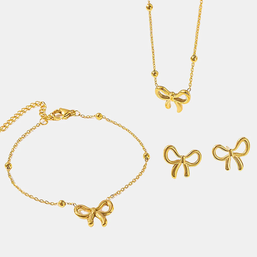 Gold jewelry set with bow designs on a light gray background