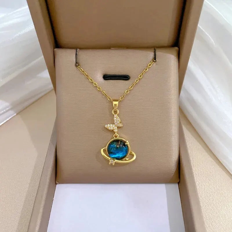 Unknown Product featuring a gold chain necklace with a blue planet pendant and butterfly detail in a gift box