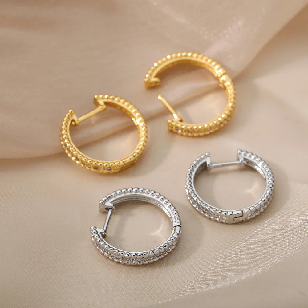 Gold and silver hoop earrings on a beige fabric background