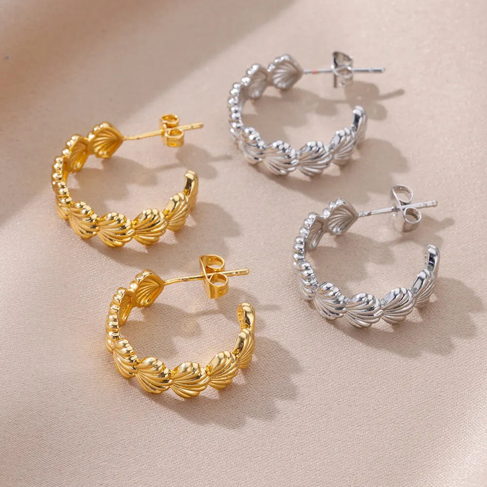 Gold and silver hoop earrings on a beige background
