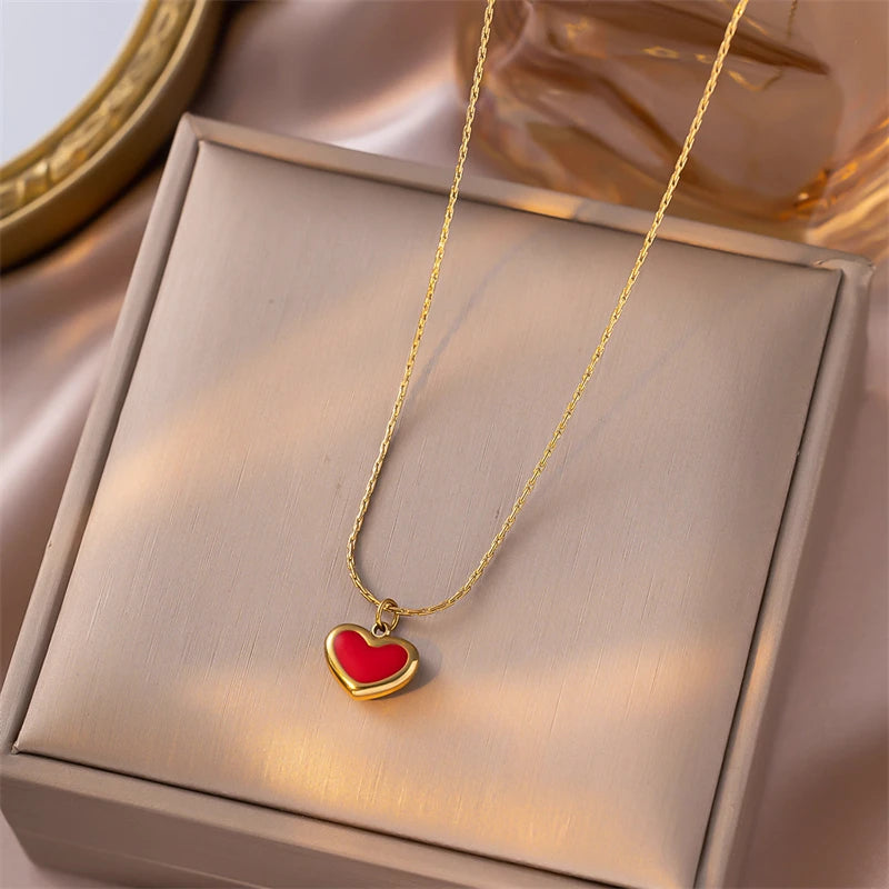Gold necklace with a red heart pendant on a beige box