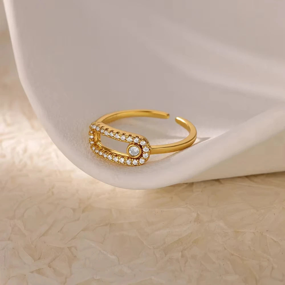 Gold bracelet with gemstones on a white ceramic dish