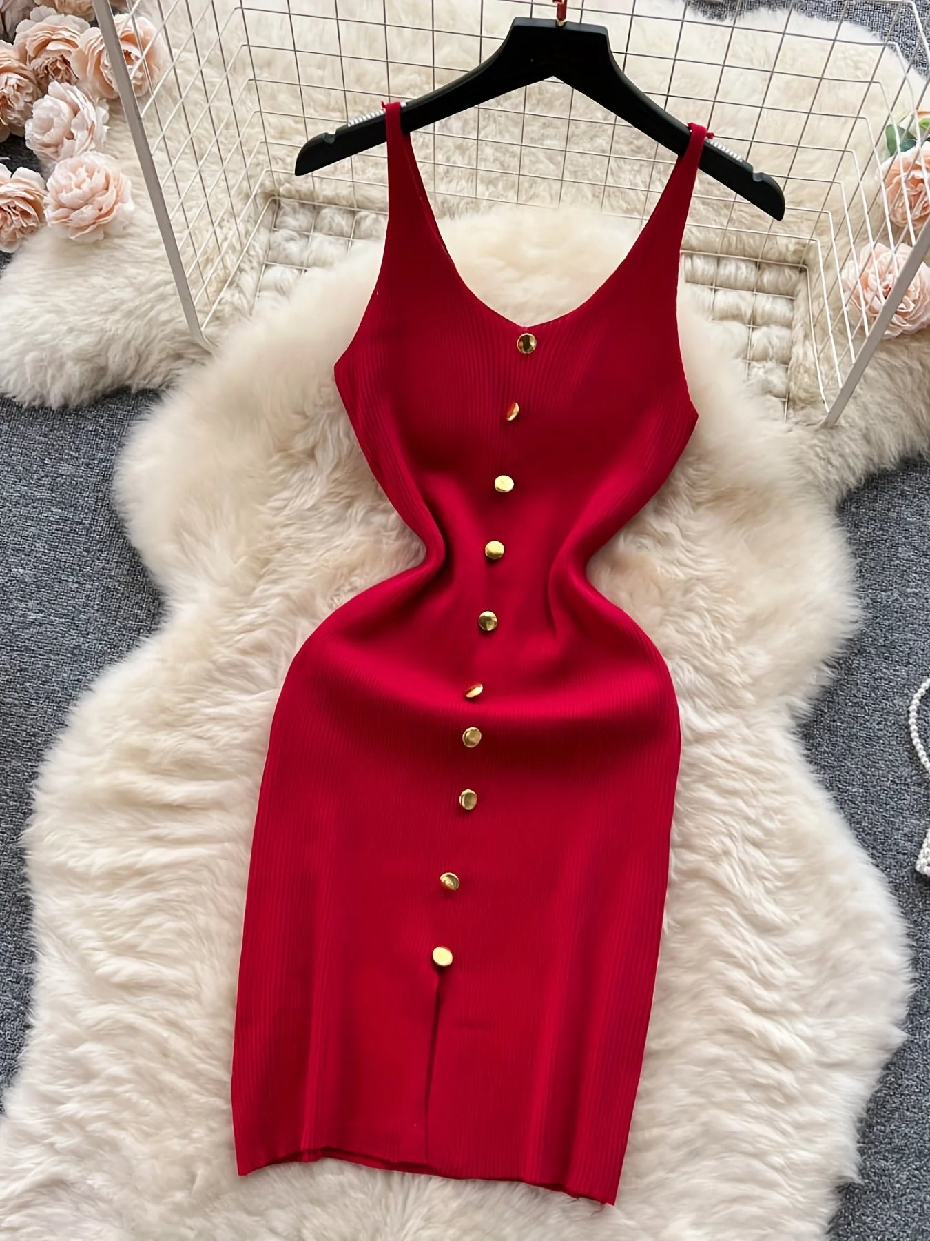 Red dress with gold buttons on a hanger against a white fur rug