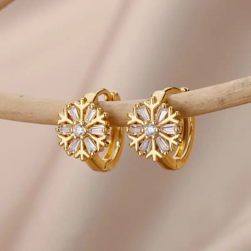 Gold hoop earrings with diamond accents on a wooden stick against a beige background