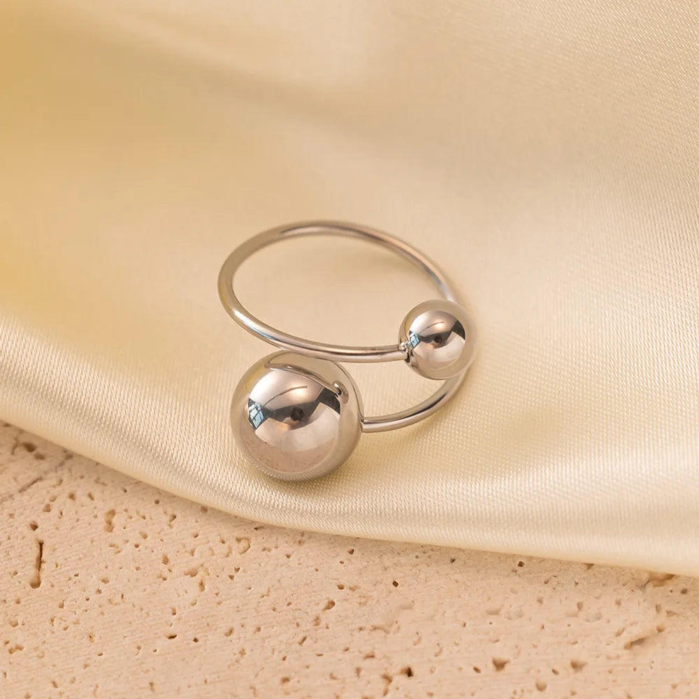 Silver ring with two spherical beads on a beige fabric background