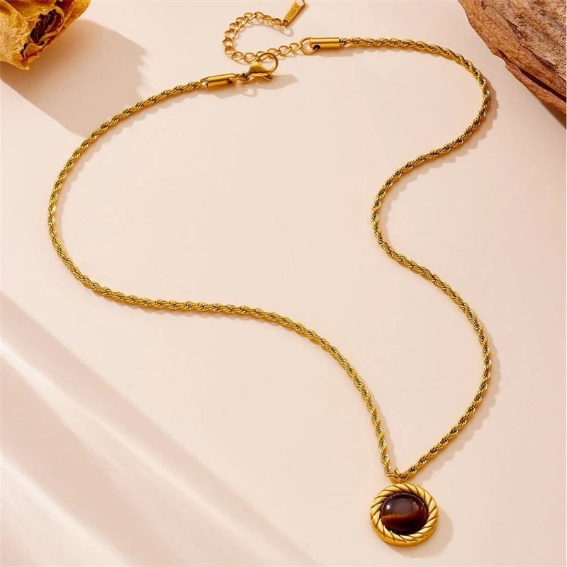 Gold necklace with a pendant on a light pink background