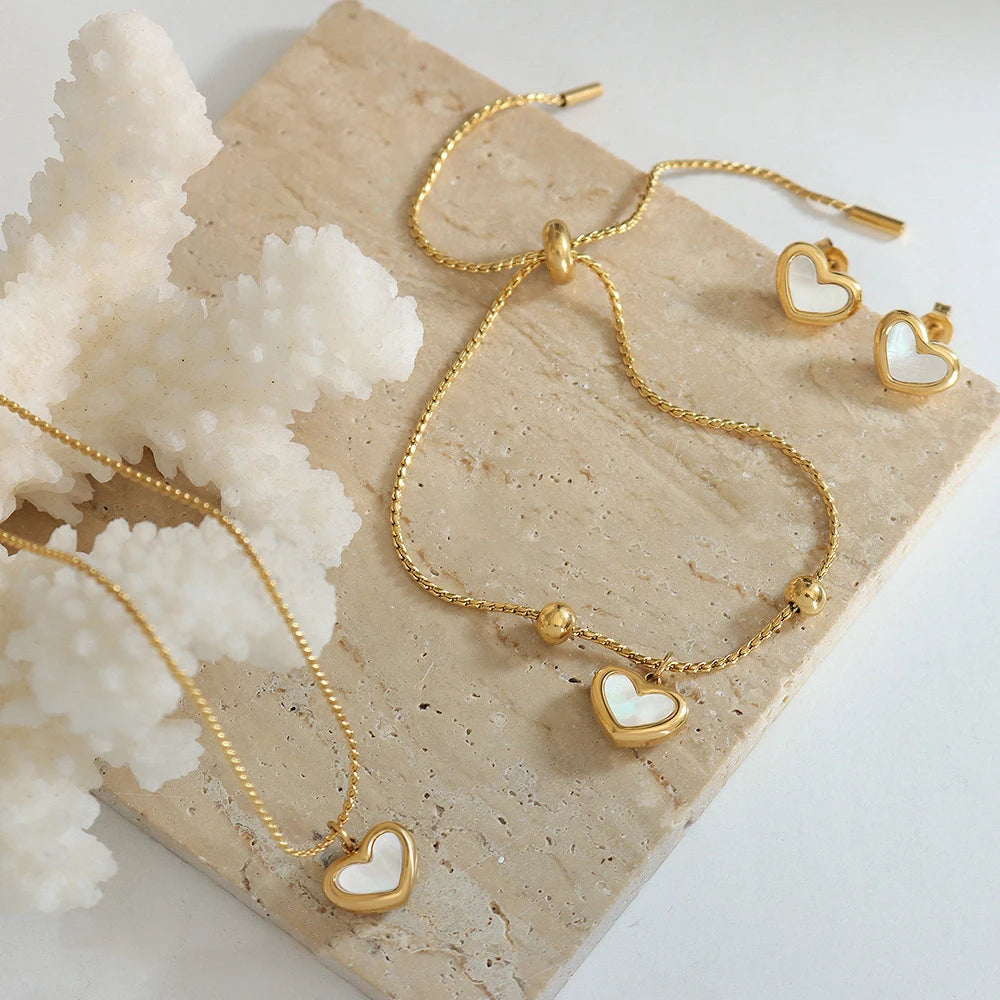 Gold jewelry set with heart-shaped pendants on a textured surface