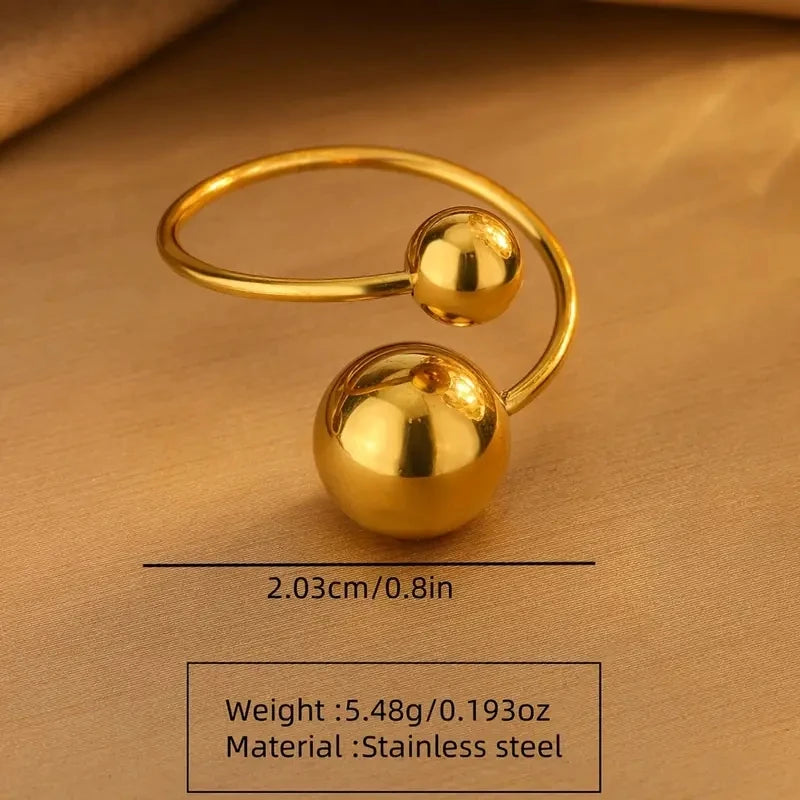 Gold ring with spherical ends on a beige background, showing measurements and material details.