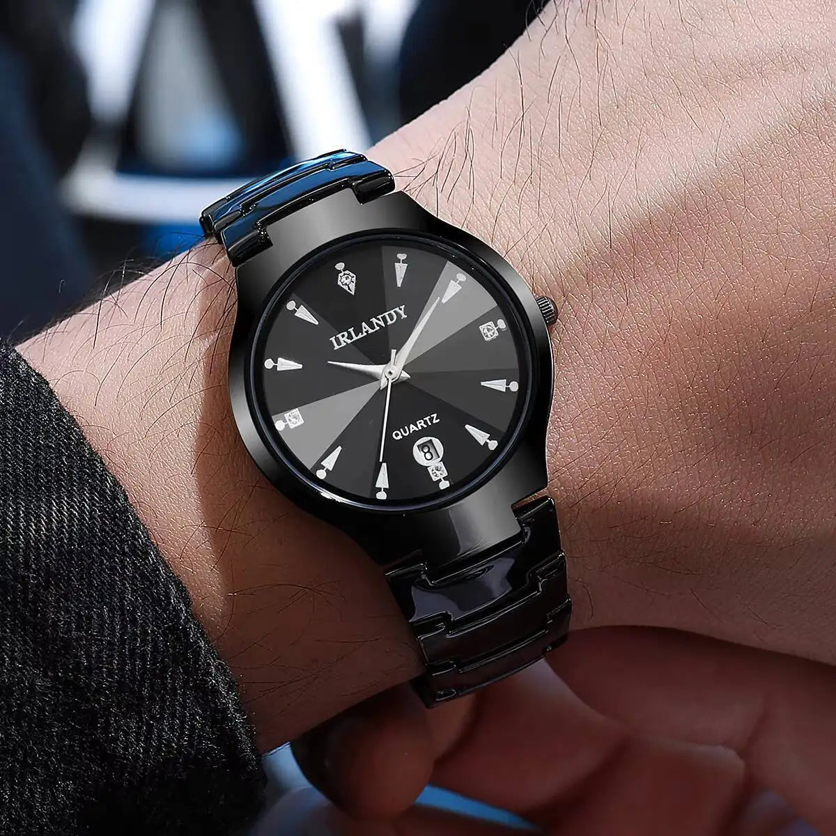 Black wristwatch on a person's wrist with a blurred background