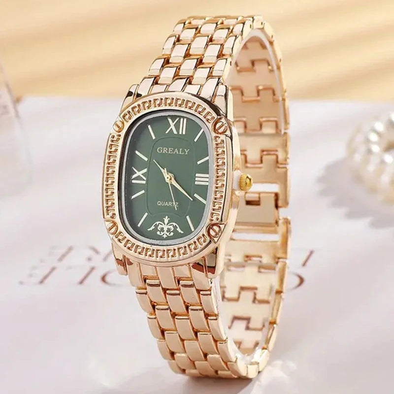 Gold wristwatch with a green dial on a white surface