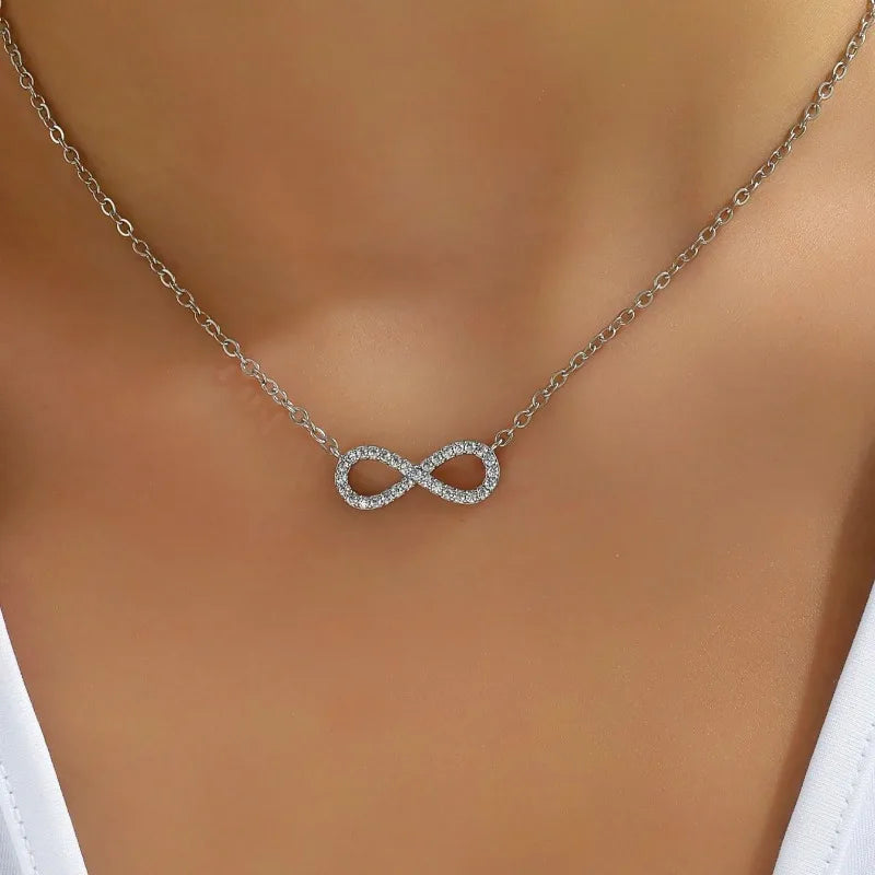 Silver infinity necklace on a mannequin with a white top