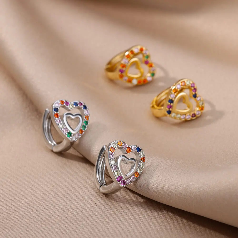Heart-shaped rings with colorful stones on a beige fabric background