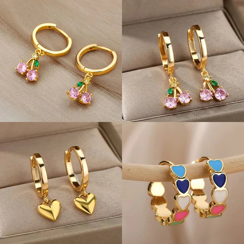 Gold hoop earrings with heart and cherry charms on a beige background